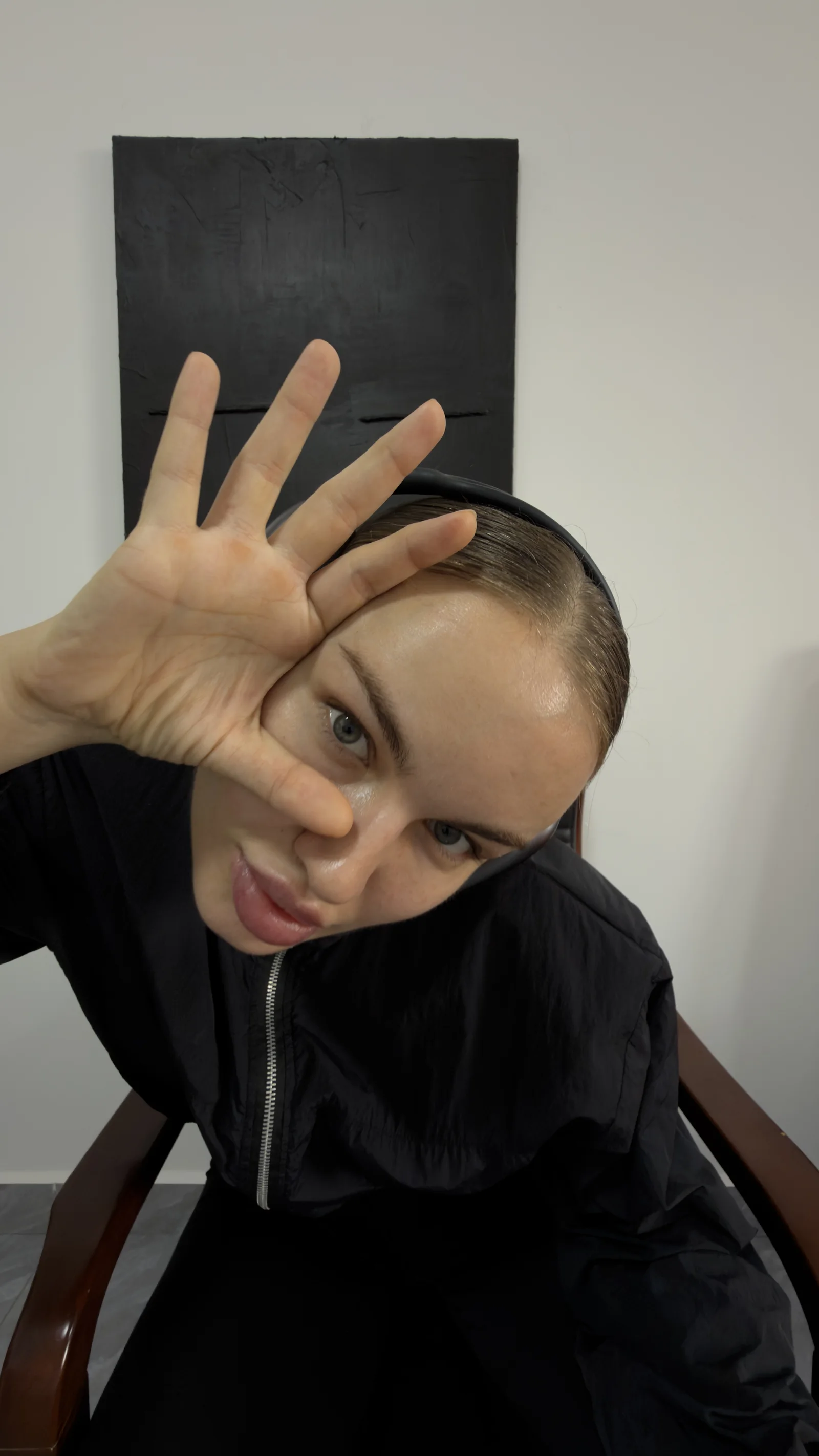 Playful close-up of Yana Chi with a hand spread in front of her face
