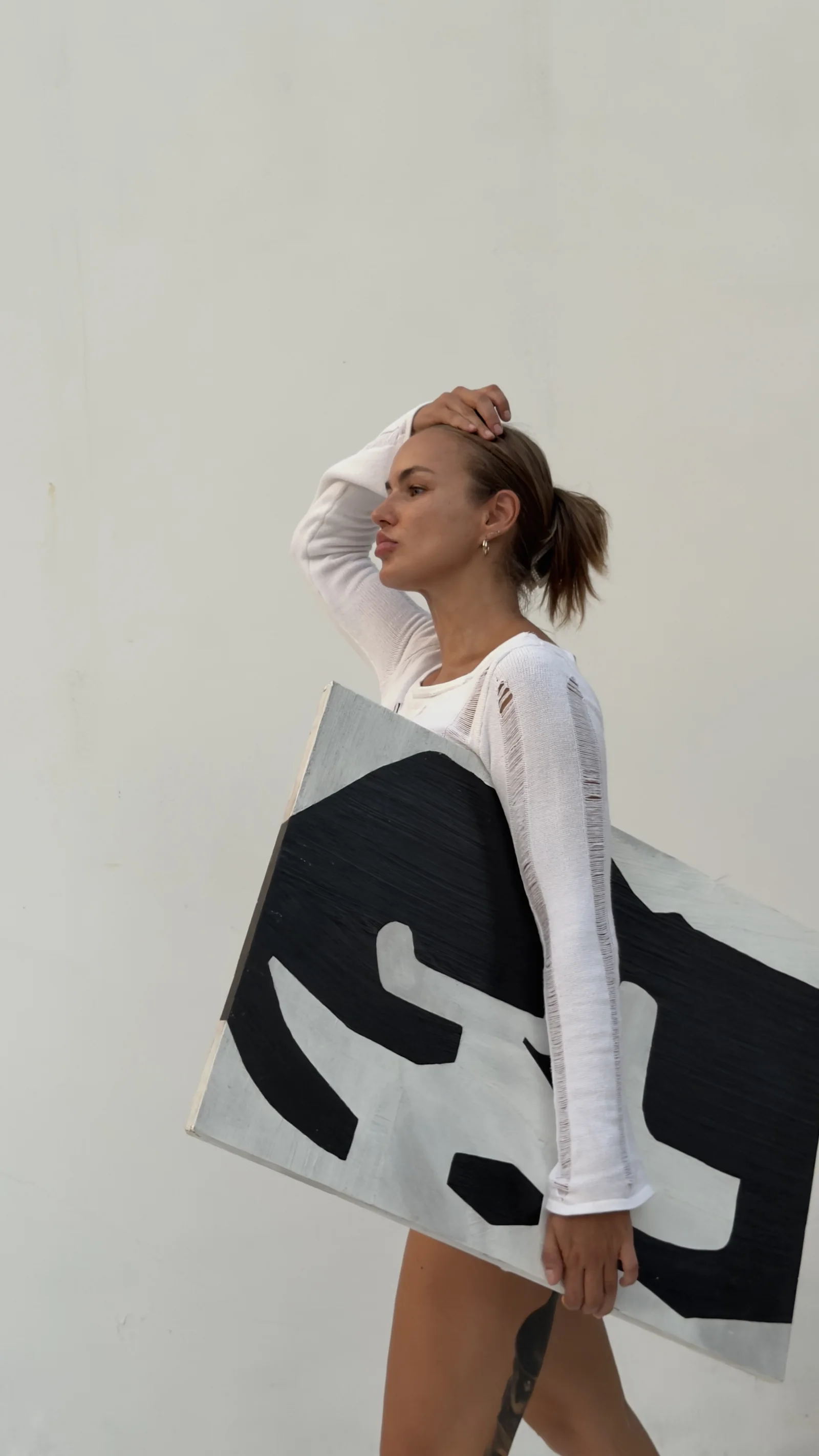 Yana Chi carrying a black and white relief panel through the studio